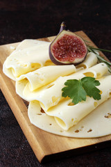 cheese slices on wooden tray with parsley. gauda cheese