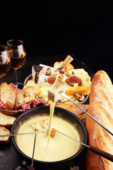 Gourmet Swiss fondue dinner on a winter evening with assorted cheeses on a board alongside a heated...