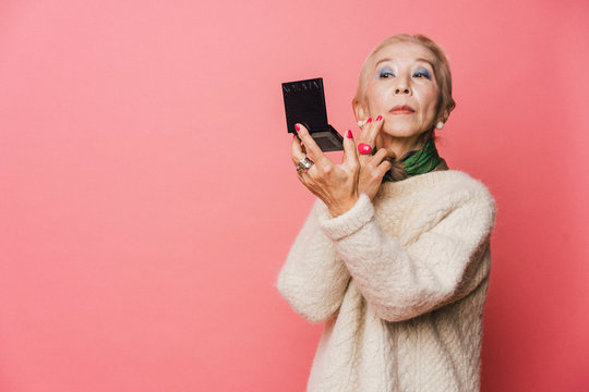 コンパクトで化粧を確認するシニア女性