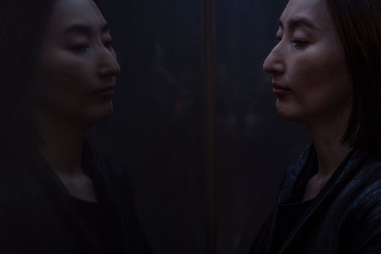 窓に映った自分の顔を見る女性のポートレート