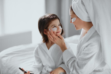 beauty concept. careful attentive mother use patches for eyes and her daughter in mask too. parents...
