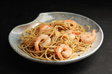 Plate of tasty buckwheat noodles with shrimps on black table