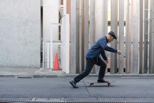 屋外でスケートボードに乗ろうとしている、ハンチング帽を被ったシニア男性のポートレート