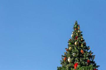 Christmas tree decorated with toys on a blue sky background. Copy space