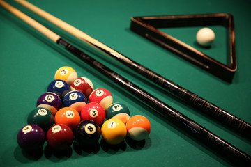 Sports game of billiards on a green cloth. Multi-colored billiard balls in the form of a triangle...