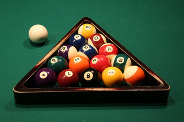 Sports game of billiards on a green cloth. Multi-colored billiard balls in a wooden triangle with...