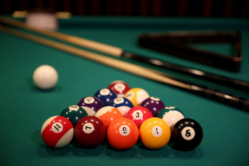 Sports game of billiards on a green cloth. Multi-colored billiard balls in the form of a triangle...