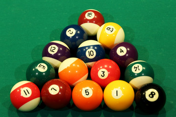 Sports game of billiards on a green cloth. Multi-colored billiard balls in the shape of a triangle with numbers on the pool table. Active leisure and entertainment. Billiards billiard balls close up.