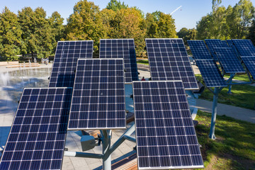 Green energy Aerial flight in a city park overlooking a panel with solar cells surrounded by trees....