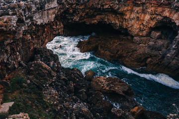 Obraz premium Waves crashing over rock formation. cliffs with caves.