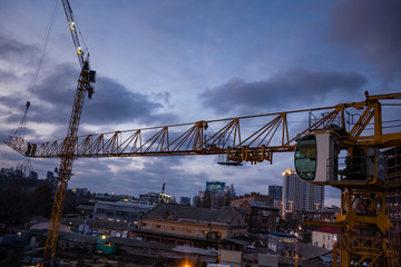 Fototapeta na wymiar Construction site and cranes in the early evening. Workers on the crane and construction site