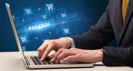 Businessman working on laptop with PAY CASH inscription, online shopping concept