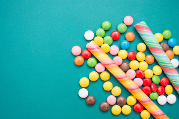 multi-colored caramel on a green background. Lollipops in the form of a cane, jelly beans and...