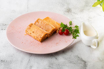 Savory crepe rolls with ground meat filling served with tomatoes. Traditional Russian Shrovetide Maslenitsa festival meal isolated on white marble background. Homemade food. . Hotizontal photo.