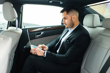 Fototapeta na wymiar Confident man in tuxedo sit using laptop, working in car, man with beard