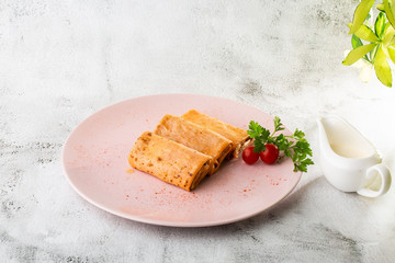 Savory crepe rolls with ground meat filling served with tomatoes. Traditional Russian Shrovetide Maslenitsa festival meal isolated on white marble background. Homemade food. . Hotizontal photo.