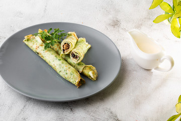 Savory Homemade Mushroom and Spinach green Crepes with Cheese isolated on white marble background. Homemade food. Tasty breakfast. Selective focus. Hotizontal photo.