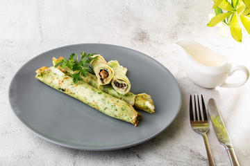 Savory Homemade Mushroom and Spinach green Crepes with Cheese isolated on white marble background. Homemade food. Tasty breakfast. Selective focus. Hotizontal photo.