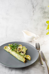 Savory Homemade Mushroom and Spinach green Crepes with Cheese isolated on white marble background. Homemade food. Tasty breakfast. Selective focus. Vertical photo.