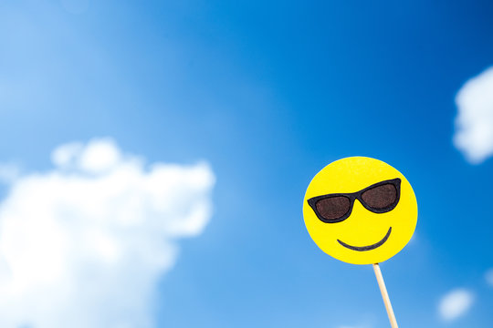 KYIV, UKRAINE - MAY 25, 2019: paper cut smiling face in sunglasses emoji