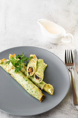 Savory Homemade Mushroom and Spinach green Crepes with Cheese isolated on white marble background. Homemade food. Tasty breakfast. Selective focus. Vertical photo.