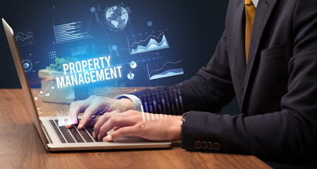 Businessman working on laptop with PROPERTY MANAGEMENT inscription, new business concept