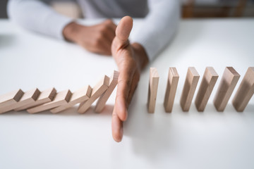 Businessman Stopping The Effect Of Domino