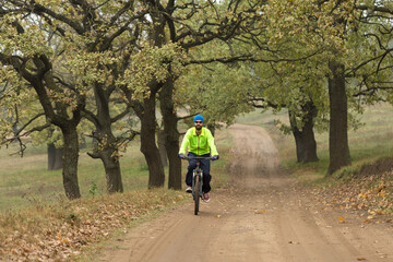 Cyclist in pants and fleece jacket on a modern carbon hardtail bike with an air suspension fork rides off-road.	