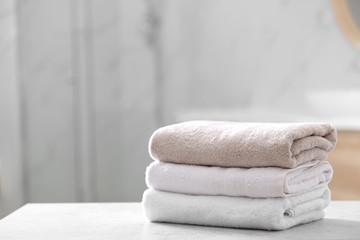 Stack of clean towels on table in bathroom - obrazy, fototapety, plakaty