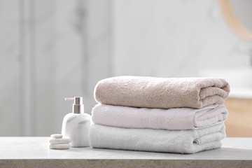 Clean towels, spa stones and soap dispenser on table in bathroom