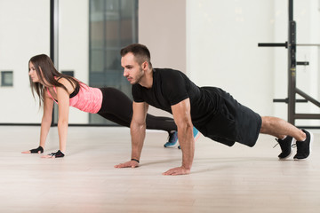 Young Couple Doing Pushups In The Gym