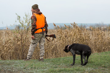 Hunting period, autumn season open. A hunter with a gun in his hands in hunting clothes in the...
