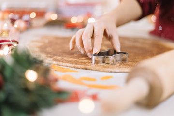 Closeup of a woman hand pressing a man-shaped cutter on cookie dough
