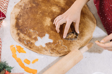 High angle view of a woman cutting gingerbread biscuits into cooking dough