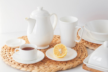 White ceramic tableware, fibre braided round placemat and cutlery set on white background. Scandinavian style