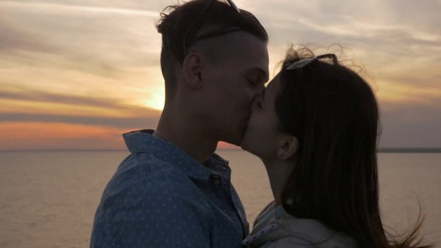 Passionate man kissing his tender girl at nice sea sunset in slo-mo