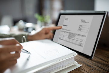 Businessman's Hands Working On Invoice On Laptop