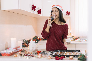 Smiling lady drinking wine and decorating gingerbread cookies