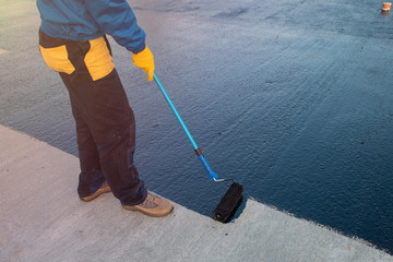 Worker applies bitumen mastic on the foundation
