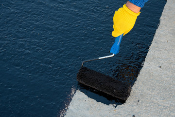 Worker applies bitumen mastic on the foundation