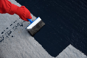 Worker applies bitumen mastic on the foundation