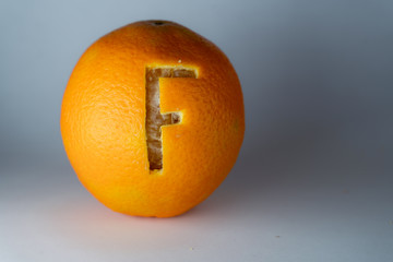 Buchstabe f einer Schriftart in die Schale frischer Orangen geschnitzt