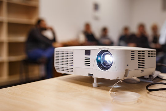 LCD video projector at business conference or lecture in a conference room or office with blurred people background