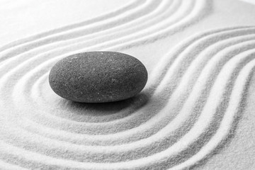 Fototapeta na wymiar Grey stone on sand with pattern. Zen, meditation, harmony