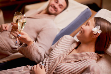 Beautiful caucasian couple in love relax spending time in spa center together, enjoy spa procedures, drinking champagne. isolated room