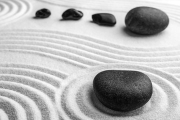 Fototapeta na wymiar Black stones on sand with pattern. Zen, meditation, harmony