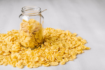 Corn flakes in a glass jar on white wooden surface. Place for your text