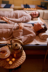 Attractive caucasian woman and man spend time in spa salon and enjoy drinking tea