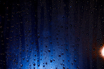 Closeup water drops on window glass and night lights in the background