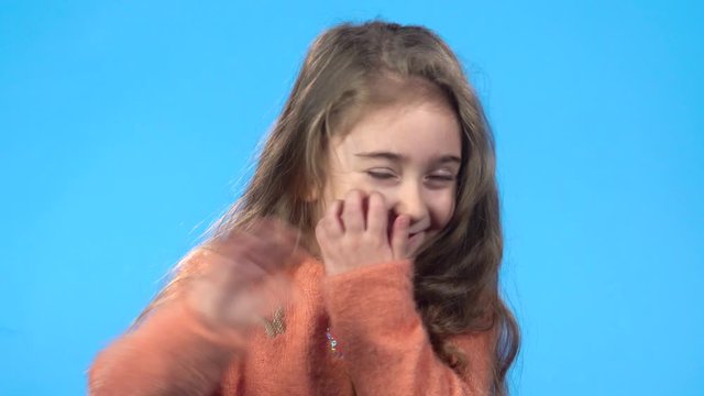 Girl laughing, waving her hand saying hello and calling someone.